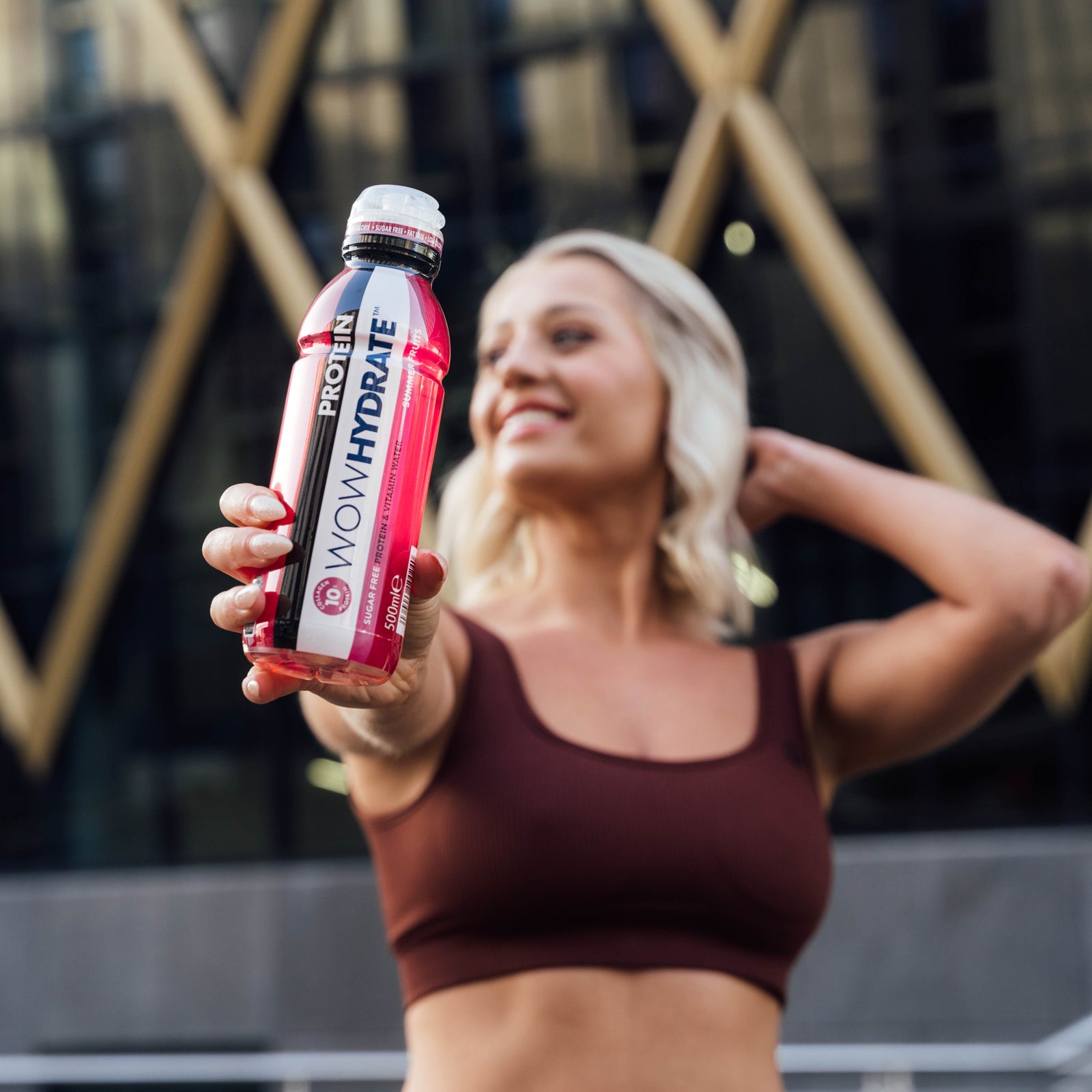 Wowhydrate protein bottle being held by a woman wearing gym attire